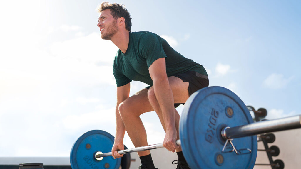 Male ectomorph doing strength workout with barbell