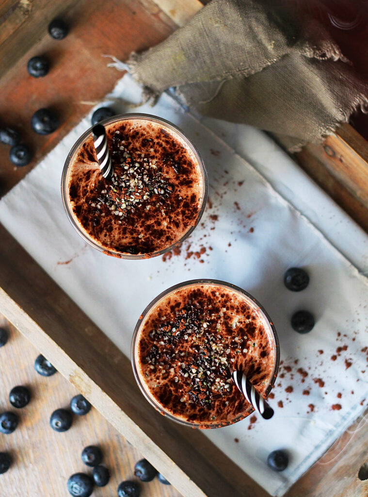 Two glasses of chocolate smoothie with blueberries