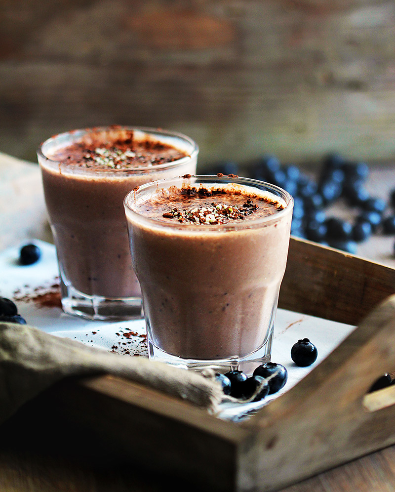 Two glasses of chocolate smoothie with blueberries